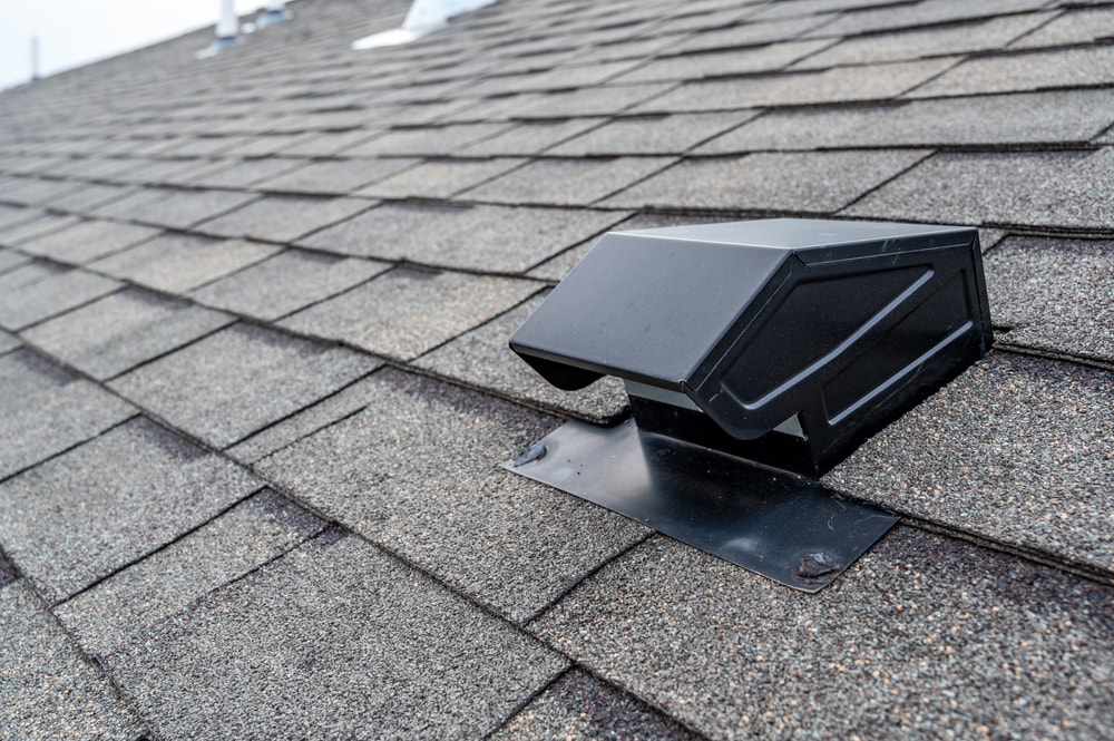 Close-up of a roof with gray asphalt shingles and a black roof vent, expertly installed by a roofing contractor Suffolk County. The even shingle layers reflect quality home improvement Suffolk County, NY homeowners can trust.