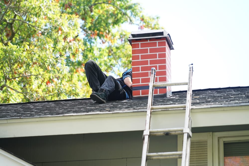 Worker Repairing Chimney On The Roof in Suffolk County, NY